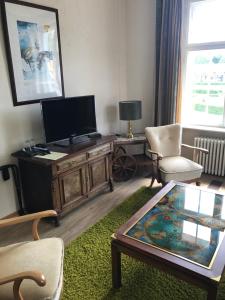 a living room with a tv and a coffee table at Bahnhofshotel Die Neue Bühne in Bad Saarow