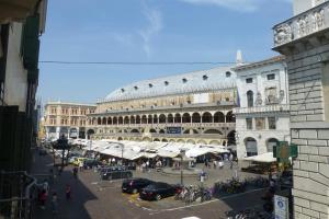 une place de la ville avec un grand bâtiment avec des voitures garées dans l'établissement PadovaResidence Apartments - vista Piazza delle Erbe e Palazzo della Ragione, à Padoue