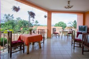 ein Esszimmer mit einem Tisch und Stühlen sowie einem Balkon in der Unterkunft La Grand Chez Johnson Hotel Muyenga in Kampala