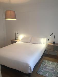 1 dormitorio con 1 cama blanca grande y 2 lámparas en Santiago City Center, en Santiago de Compostela