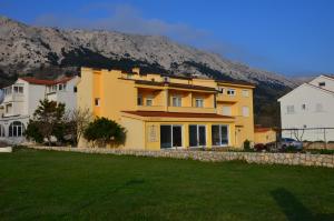 ein gelbes Haus mit einem Berg im Hintergrund in der Unterkunft Apartments Mango II in Baška