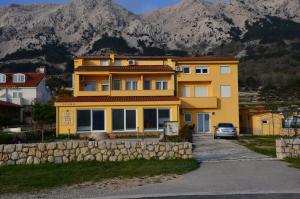 ein gelbes Haus mit einem davor geparkt in der Unterkunft Apartments Mango II in Baška