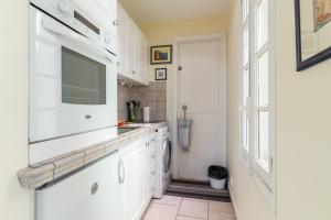 a kitchen with white cabinets and a sink and a window at Very charming studio apartment on port in Cannes a short walk to Palais with Aircon and internet 411 in Cannes