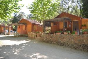 Cabañas Camping Sierra de Peñascosa في Peñascosa: منزل خشبي بحائط حجري وسياج