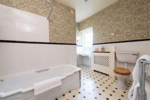 uma casa de banho com uma banheira, um WC e um lavatório. em Cavens Country House em Kirkbean