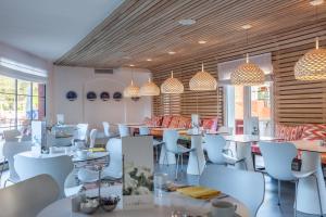 a restaurant with white tables and chairs and lights at Hotel Cala Sant Vicenç - Adults Only in Cala de Sant Vicenc