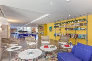 a waiting room with tables and chairs and shelves at Hotel Cala Sant Vicenç - Adults Only in Cala de Sant Vicenc