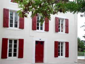 シジャンにあるLa Vadrouilleの赤いシャッター付き窓と赤いドアのある白い家