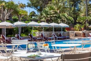 a patio with tables and chairs and a swimming pool at Hotel Cala Sant Vicenç - Adults Only in Cala de Sant Vicenc