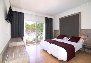 1 Schlafzimmer mit 2 Betten und einem großen Fenster in der Unterkunft Hotel Vibra Marco Polo II - Adults only in Sant Antoni de Portmany