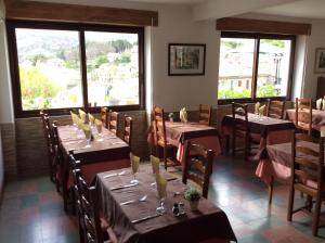 a dining room with tables and chairs and windows at Hotel Restaurant de la Poste in Aullène
