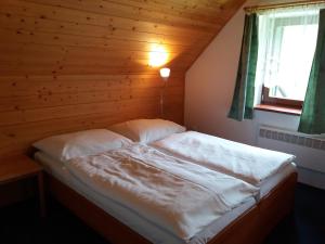 Bett in einem Zimmer mit einer Holzwand in der Unterkunft Horska chata Svetlanka in Rokytnice nad Jizerou