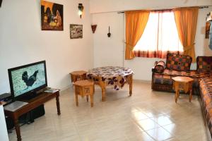 sala de estar con TV, mesa y sillas en Appartement 400m plage 4eme étage en El Jadida