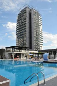 a large swimming pool with a tall building in the background at Burgas Beach Hotel in Sunny Beach