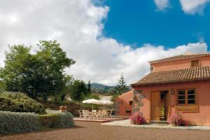 una casa con sillas y sombrillas y un patio en Casa Rural El Adelantado, en Tacoronte