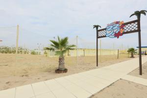 a sandy beach with a palm tree and a sign at Hotel Europa in Rimini