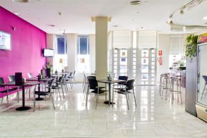 a restaurant with tables and chairs and pink walls at Hotel Traíña in San Pedro del Pinatar