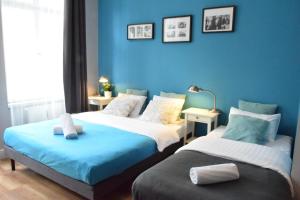 two beds in a room with blue walls at Blooms Inn & Apartments in Poznań