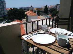 uma mesa de madeira com pratos e utensílios numa varanda em As Mimosas em Sesimbra