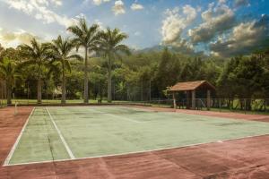 a tennis court with a gazebo and palm trees at Hotel Moradas do Penedo in Penedo