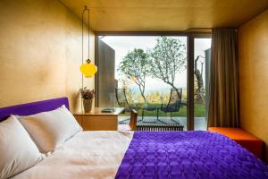 a bedroom with a purple bed and a balcony at Casa das Penhas Douradas - Burel Expedition Hotel in Manteigas