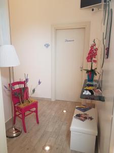 una stanza con una sedia rossa, un tavolo e una porta di Di Ma B&B a Porto Cesareo