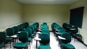 an empty classroom with green chairs and a chalkboard at Hotel Majú in Rio Branco