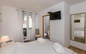 1 dormitorio con cama blanca y espejo en NORA APARTMENT by DuHomes, en Dubrovnik