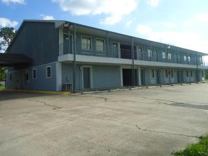 a large building with a parking lot in front of it at Super 6 Inn in Carencro