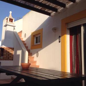 a house with a wooden table in front of a building at Gomeira Terrace in Cabanas de Tavira