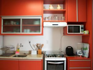 a kitchen with red cabinets and a stove and microwave at Duplex com hidromassagem - Praia do Forte in Praia do Forte