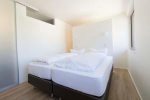 1 dormitorio con 2 camas blancas y espejo en MAVO Hospitality by Büroma Apart Apartmentvermietung GmbH Esslingen en Esslingen