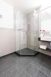uma casa de banho com uma cabina de duche em vidro e um lavatório. em MAVO Hospitality by Büroma Apart Apartmentvermietung GmbH Esslingen em Esslingen