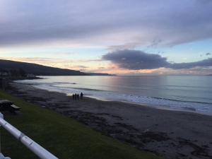 a group of people standing on the beach at sunset at Ballygally seaview apartment in Carncastle
