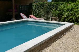 a swimming pool with two lawn chairs next to it at Mas du Puits d'Amour in Orange