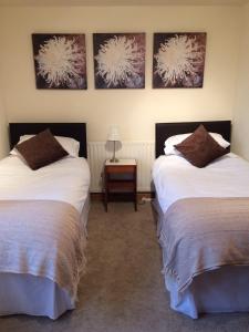 a room with two beds and a table with a lamp at The Old School B&B in Shawbury