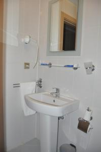 Arapgir Nazar Hotel في أرابكير: حمام أبيض مع حوض ومرآة