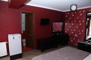 a bedroom with red walls and a white refrigerator at Hotel Obola in Samtredia