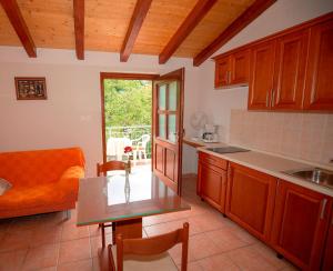 uma cozinha com armários de madeira, uma mesa e um sofá em Apartment La roza em Funtana
