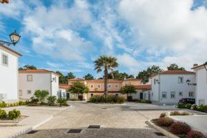 a row of houses with a palm tree in the background at T3 Vila dos Principes in Amoreira