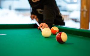 a man playing billiard with his cue on a pool table at Hotel Olympia in Axamer Lizum