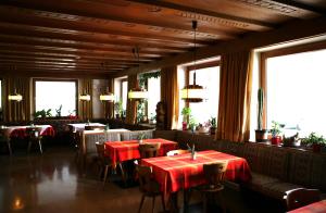 un restaurante con mesas y sillas rojas y ventanas en Residence Riposo, en Colfosco