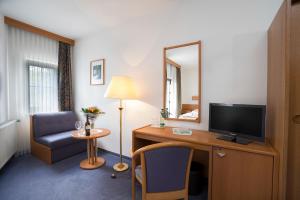 Zimmer mit einem Schreibtisch, einem TV und einem Stuhl in der Unterkunft Hotel Vogtland in Bad Elster