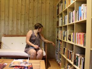 una mujer sentada frente a un estante de libros en Huttopia Beaulieu sur Dordogne, en Beaulieu-sur-Dordogne
