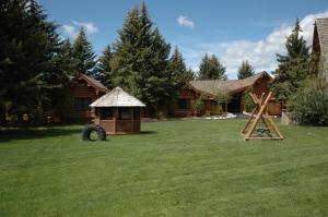 une cour avec une cabane en rondins et une aire de jeux dans l'établissement The Hatchet Resort, à Moran