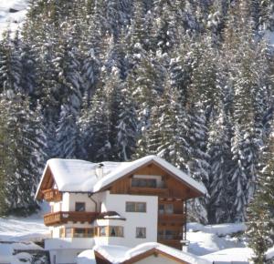 a house covered in snow with trees in the background at Apart Dorfblick in Kaunertal