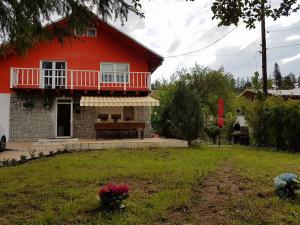 a red house with a table and a balcony at Vila Gabriela in Buşteni