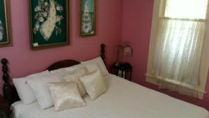 a bedroom with a white bed with pink walls at The Mays Place Bed and Breakfast in Elgin