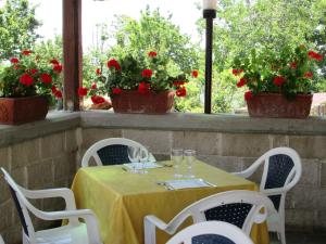 una mesa con copas de vino y flores rojas en el balcón en Mira Amalfi, en Agerola