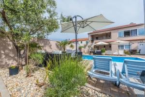a pool with two blue chairs and an umbrella at Apartments A&A in Bibinje